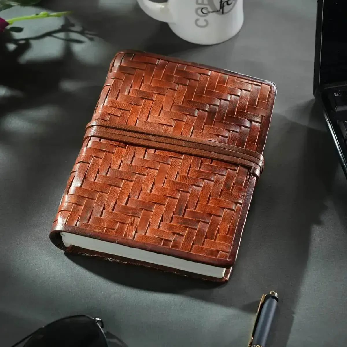 Tan woven leather journal resting on gray desk. 