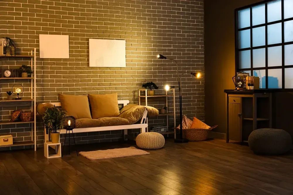 Interior of dark living room with couch, shelving units and glowing lamps.