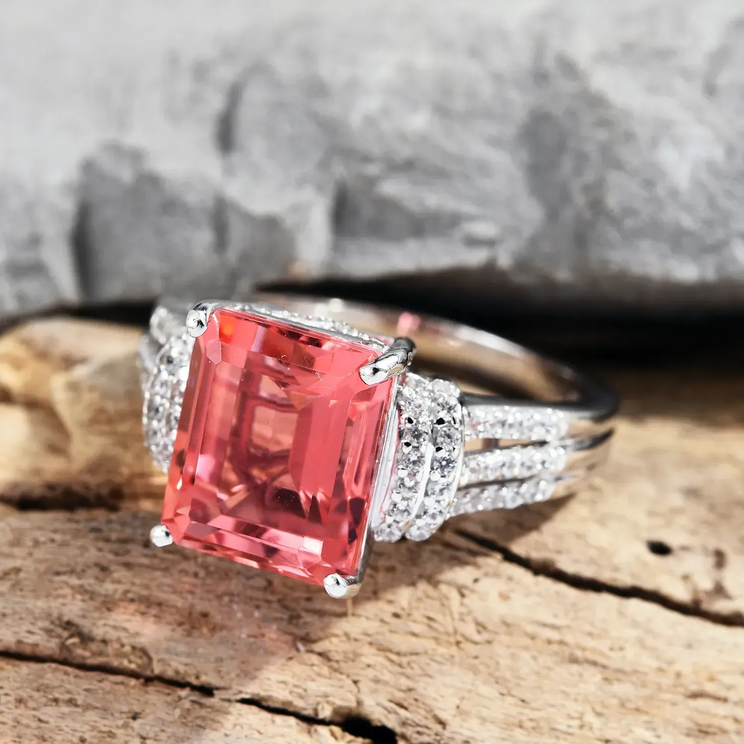 Living Coral Quartz ring resting on wood display. 