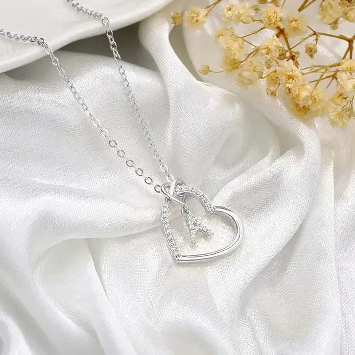 Silver initial heart pendant on white silky background.