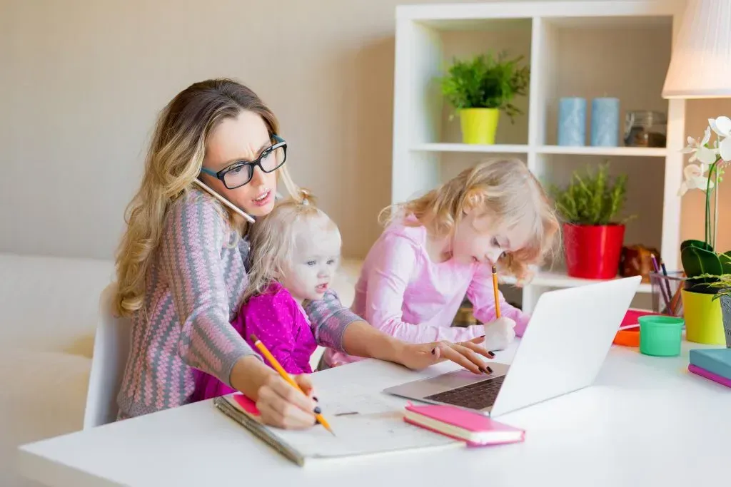 Mom working while also caring for her young children.