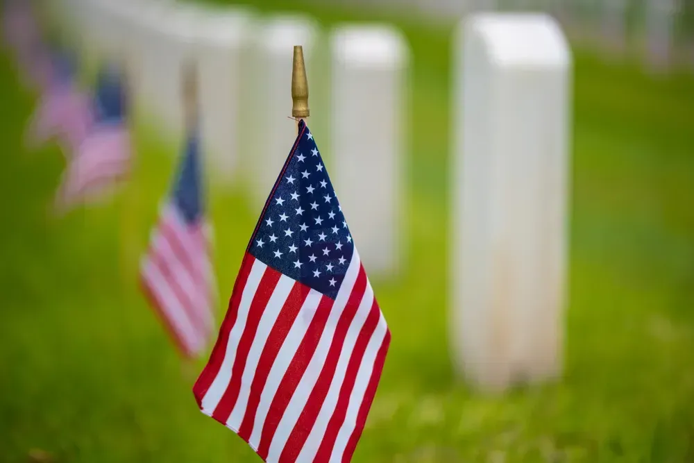 American flags marking the graves of soldiers on a clear and peaceful day.