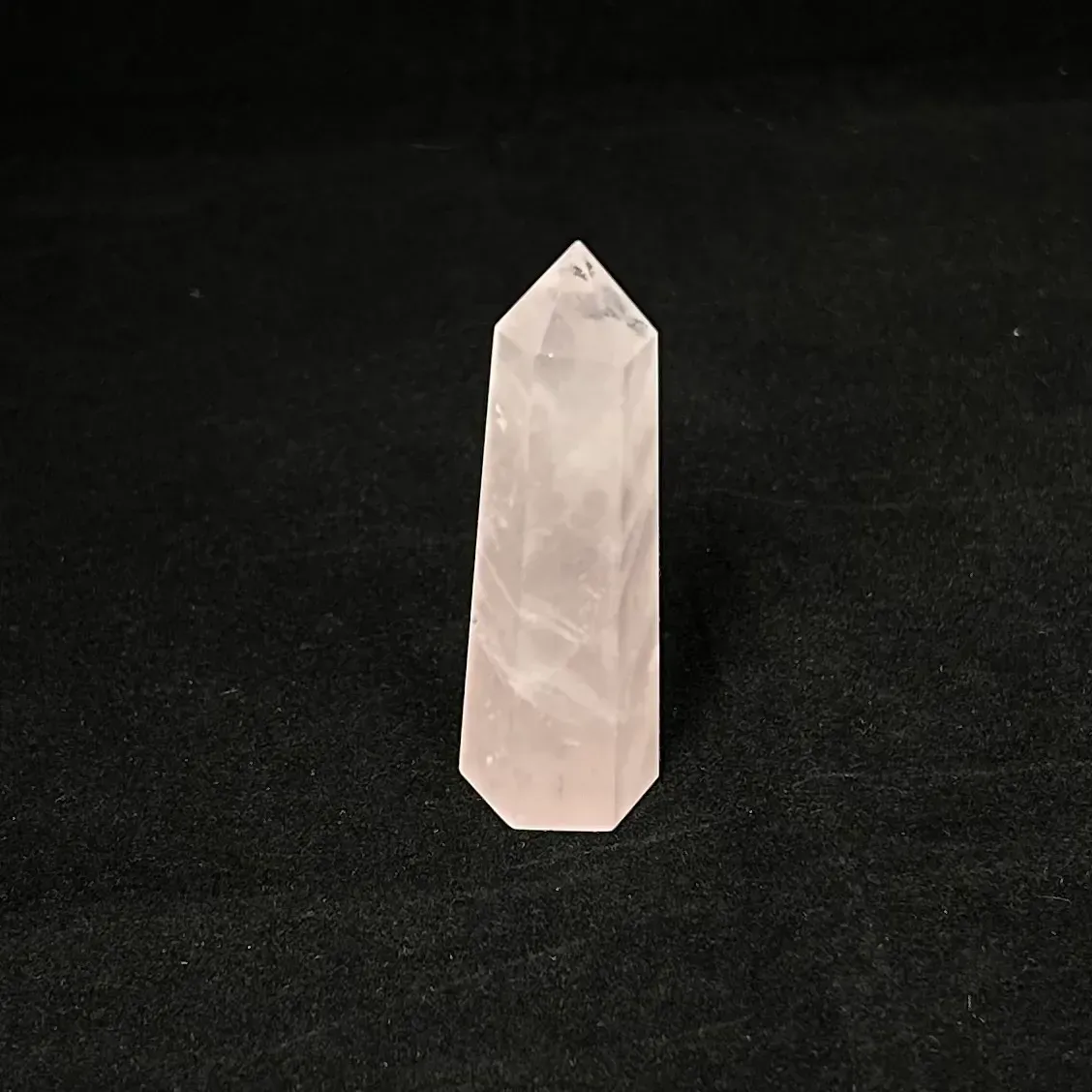 Rose quartz point against black background.