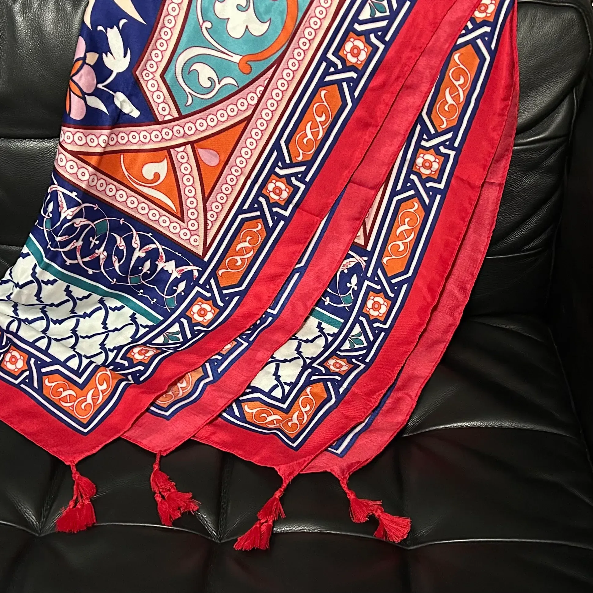 Colorful meditation shawl draped over black leather couch. 