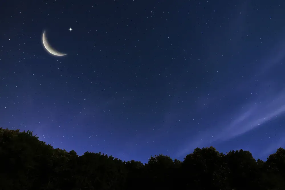 View of the night sky, with a crescent moon hanging in the upper left quadrant.