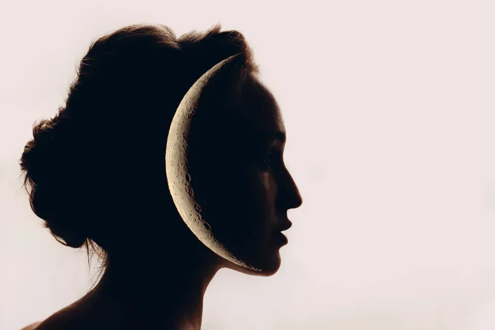 Silhouette of a woman with a crescent moon super imposed.