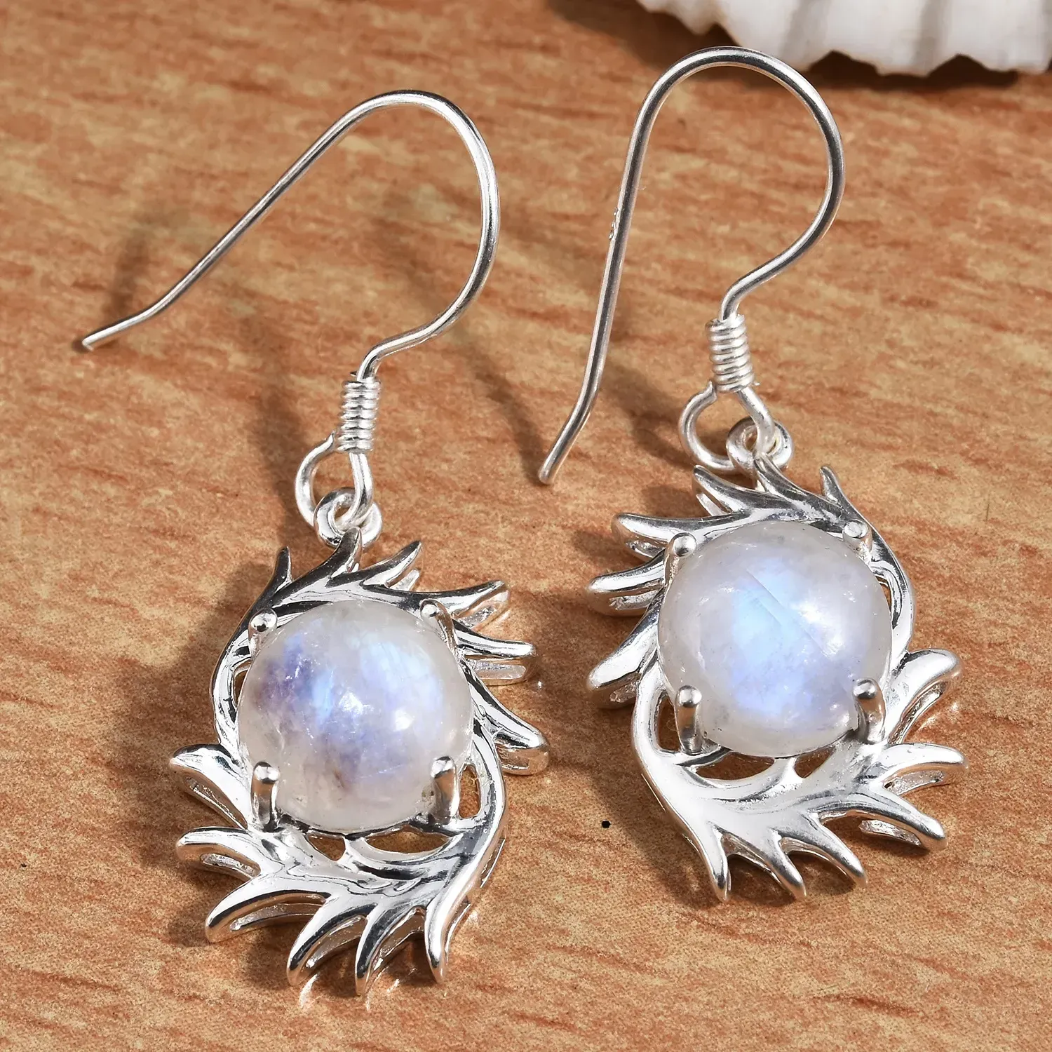 Moonstone earrings displayed on wooden board. 