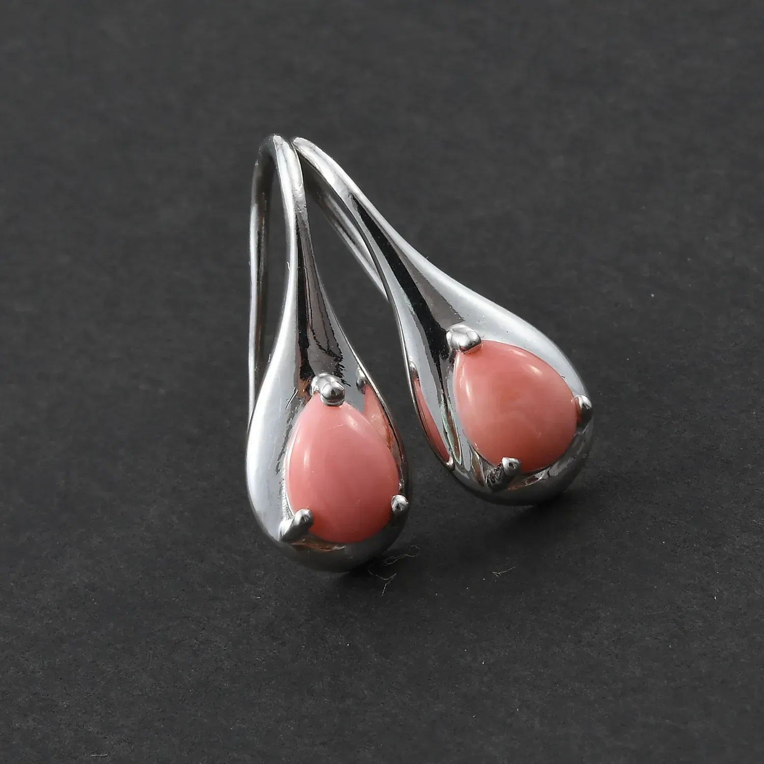 Peach opal earrings in sterling silver on black background.