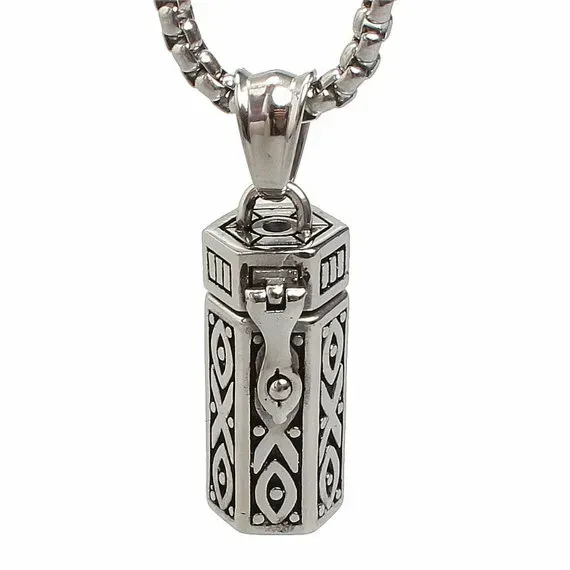 Small silver necklace containing ashes against white background.