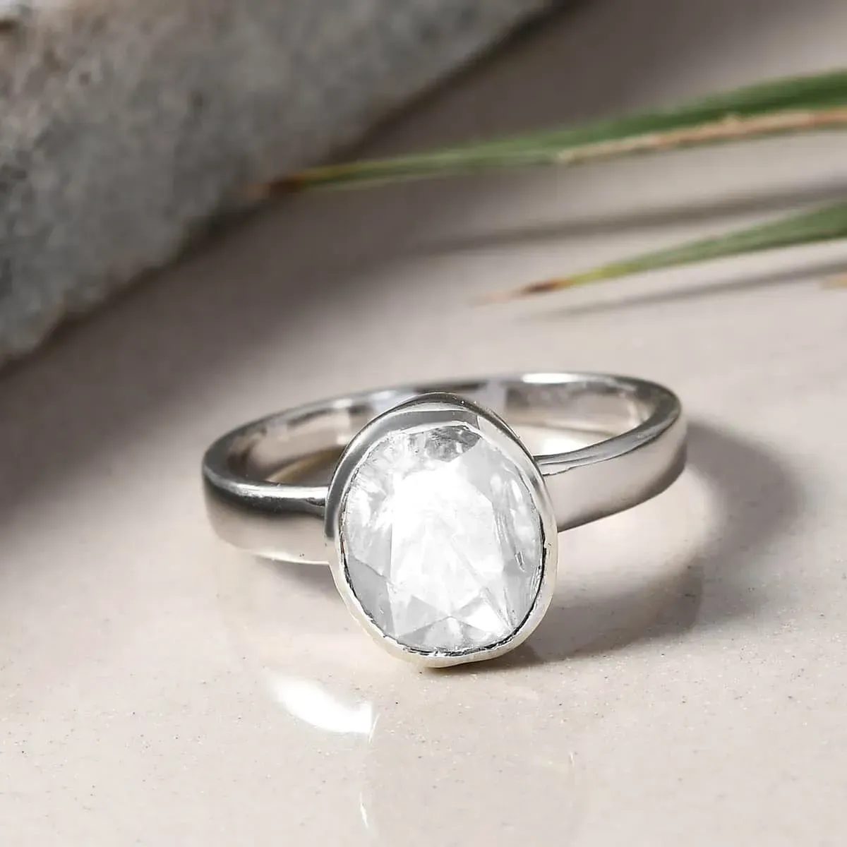Polki Moissanite Solitaire Ring in Platinum Over Sterling Silver resting on table with glossy surface. 