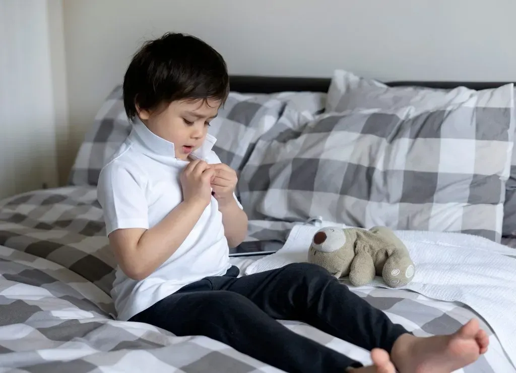 Little boy putting on school uniform.