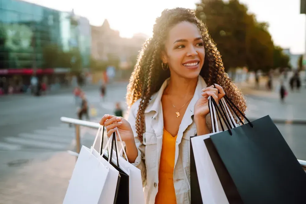 Fashionable woman with shopping bags walking on street.