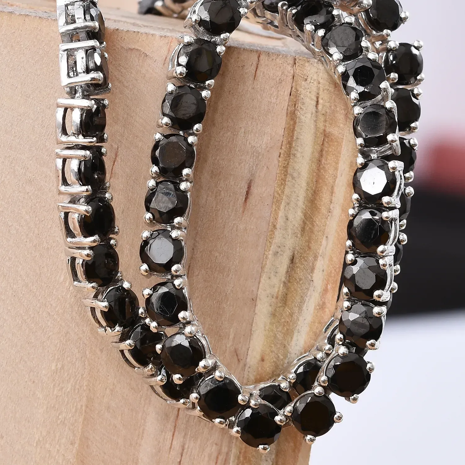 Shungite necklace draped over light colored wood.
