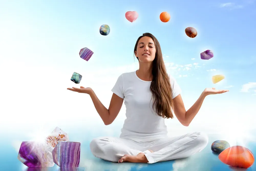A woman meditating with gemstones.
