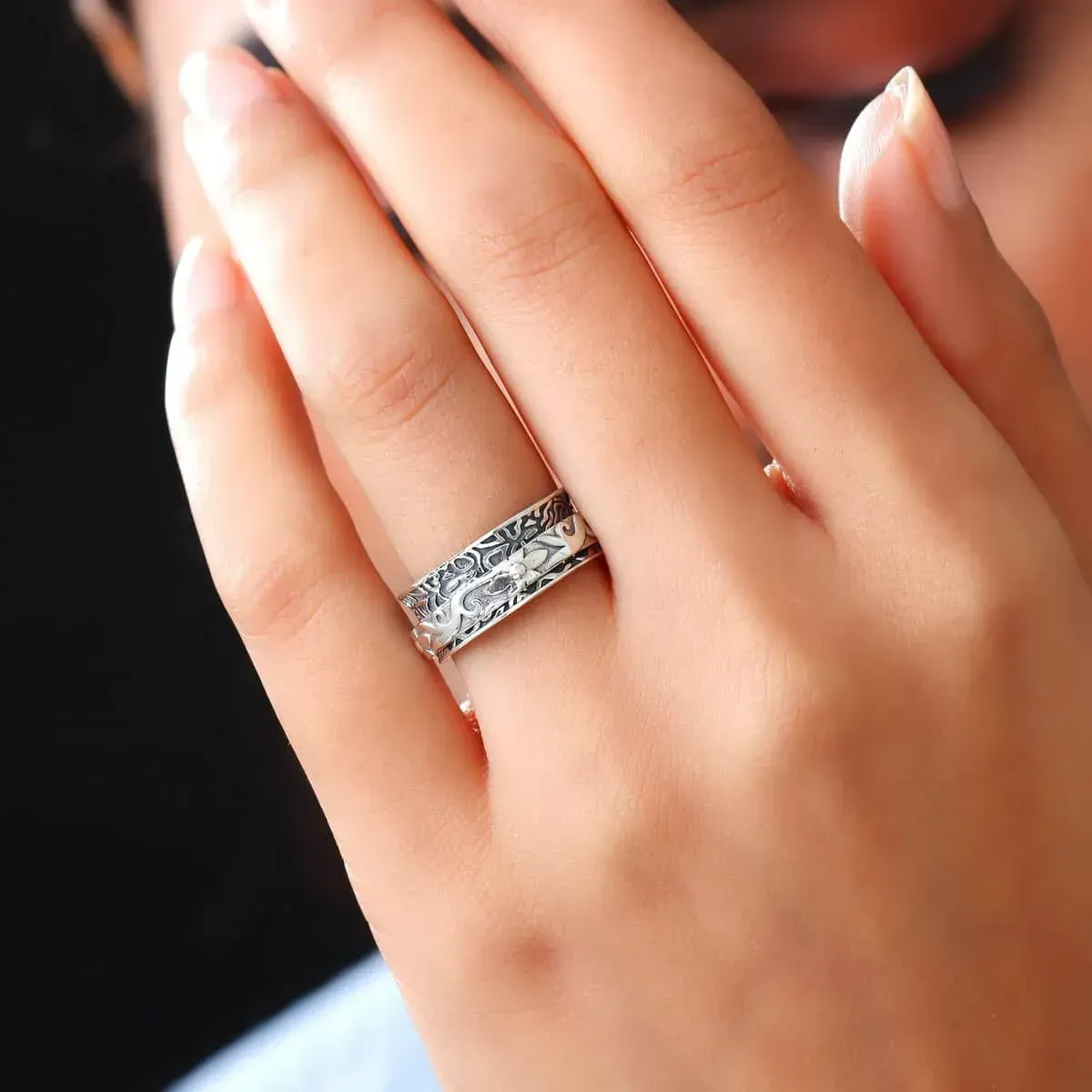 Closeup view of woman wearing a floral sterling silver spinner ring.