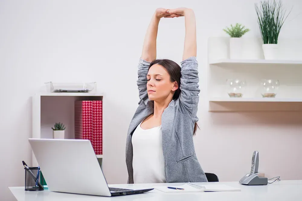 Business woman stretching at her desk.
