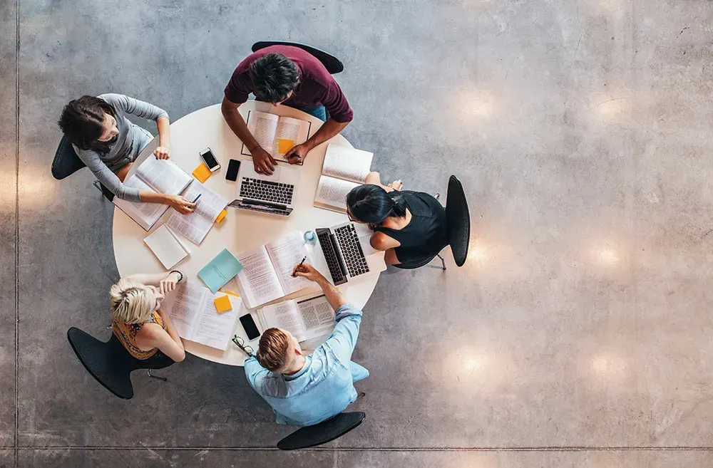 A group of students studying around a circular table.