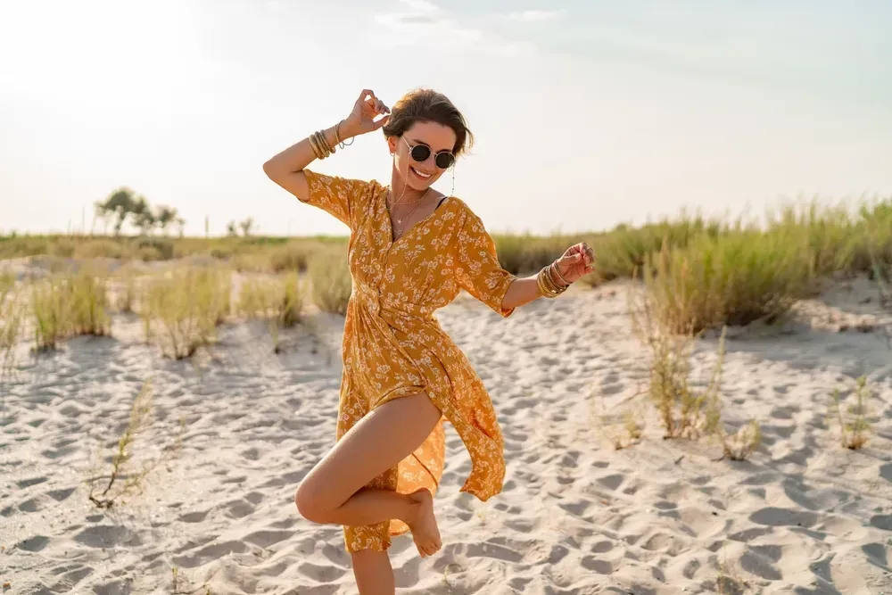 Stylish and attractive smiling woman on beach in summer fashion.
