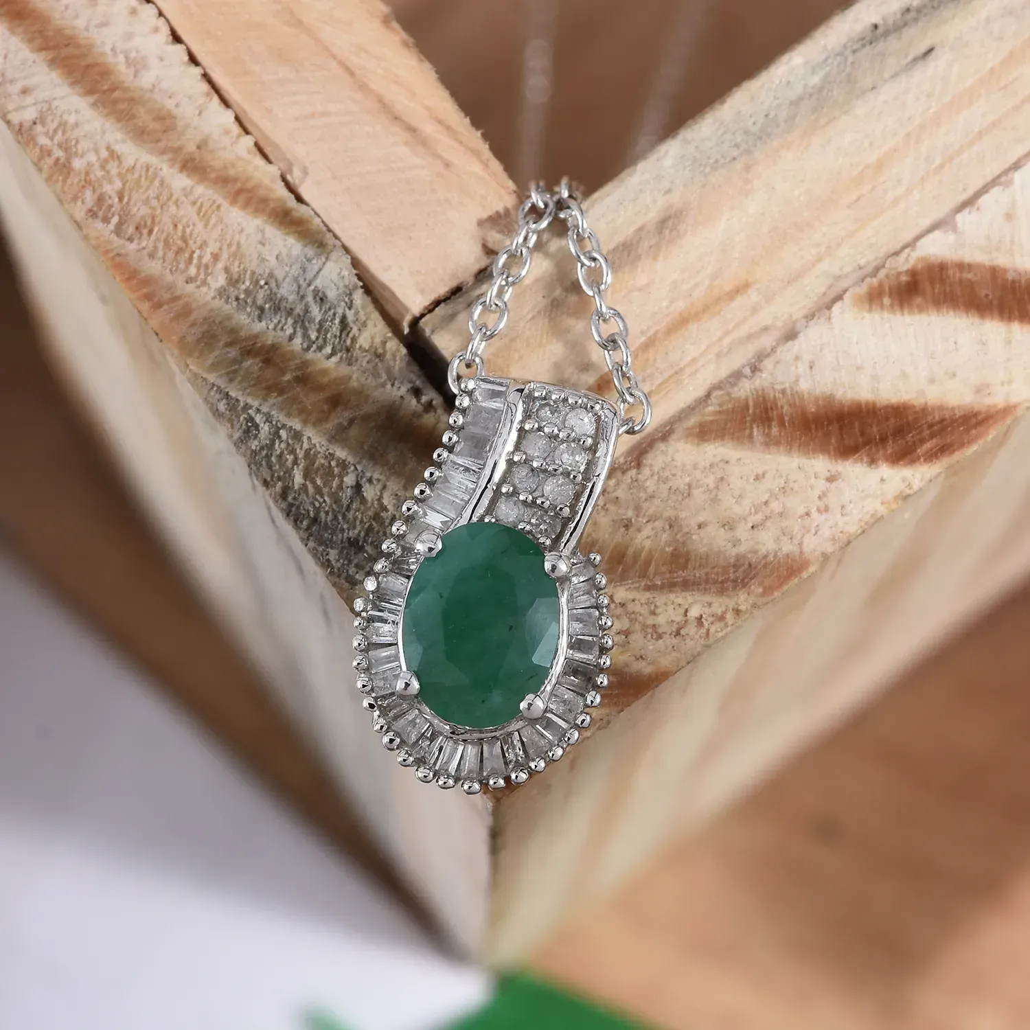 Emerald pendant draped over wooden frame.
