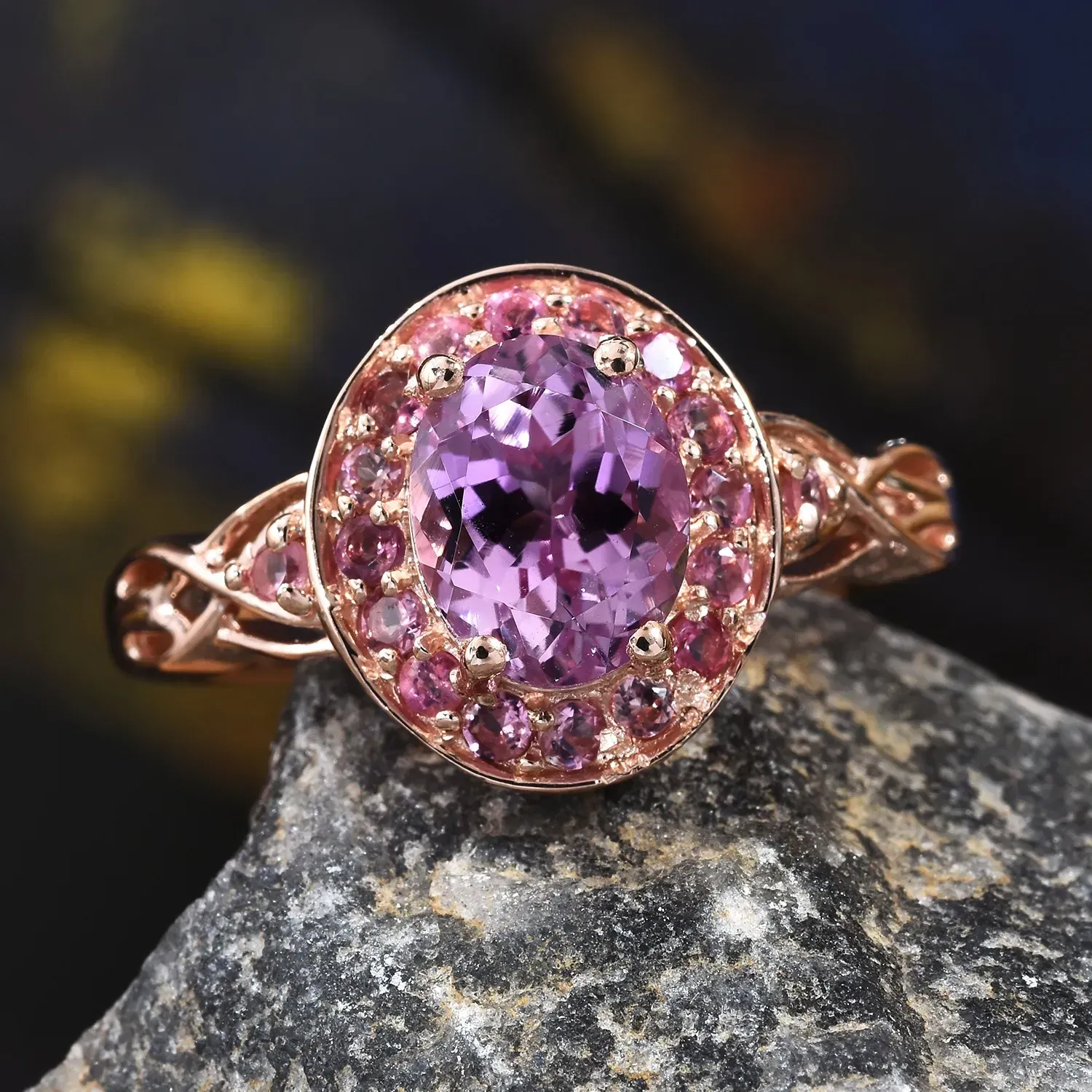 Kunzite ring in gold resting on stone. 