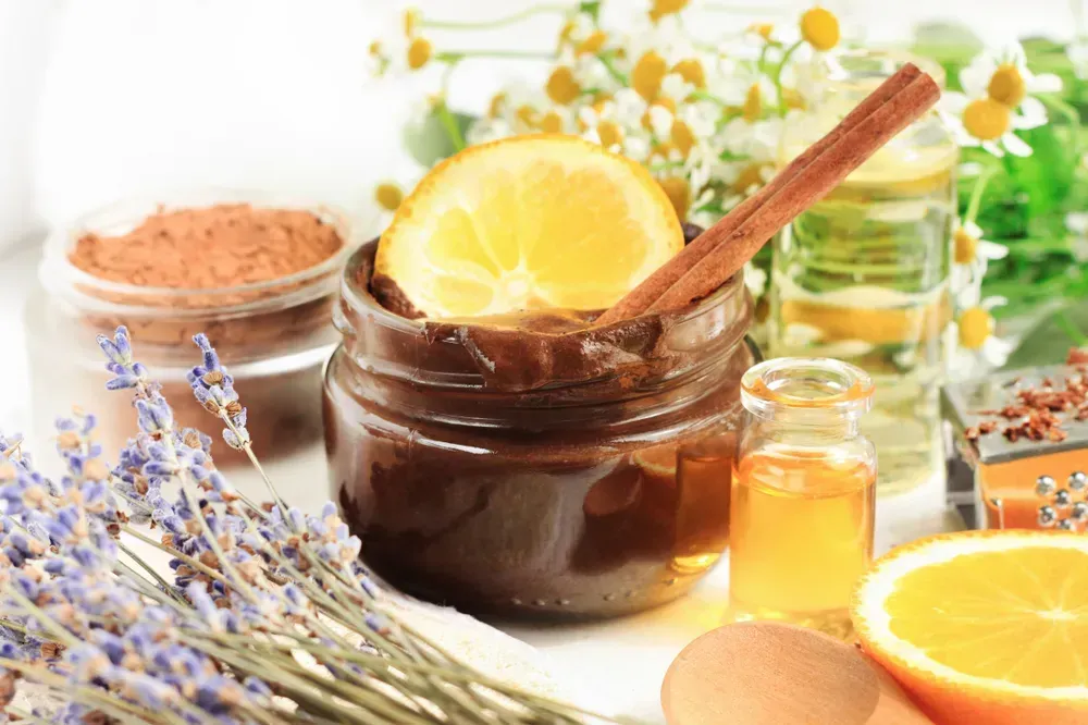 Jar of melted chocolate face mask with aroma orange oil and lavender blossom. Homemade cosmetic products source of vitamins for skincare and beauty treatment.