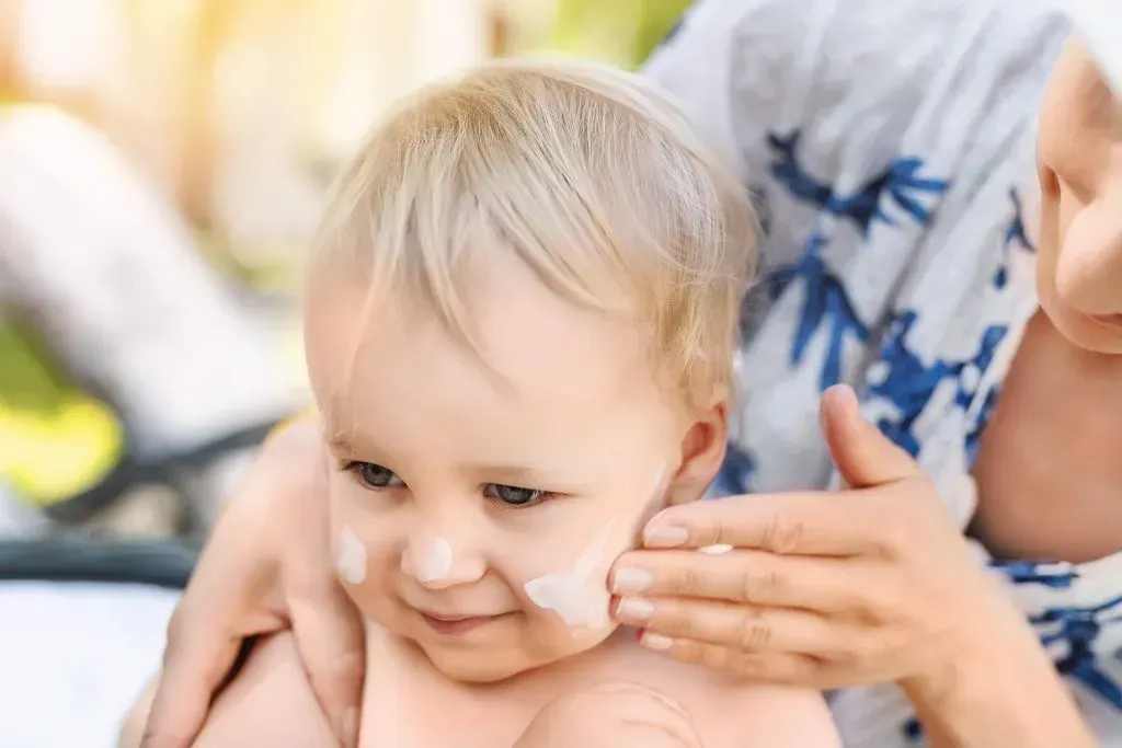 Mother applying sunscreen to child.