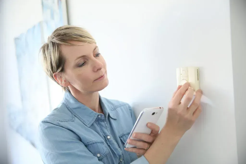 Woman adjusting her thermostat.
