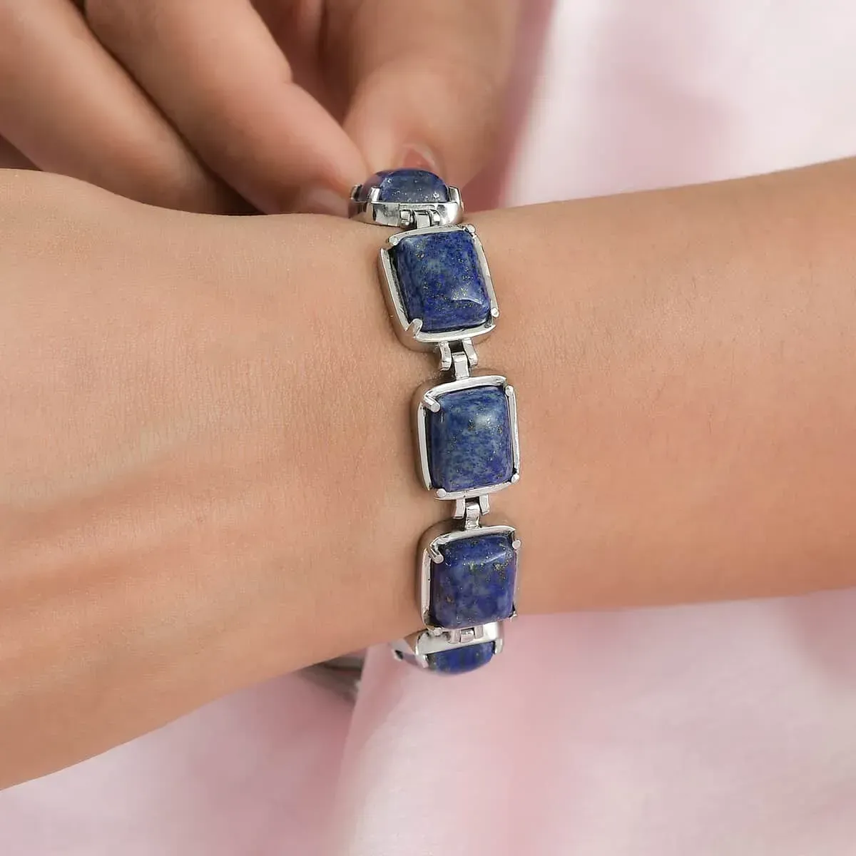 Woman adjusting lapis lazuli bracelet. 