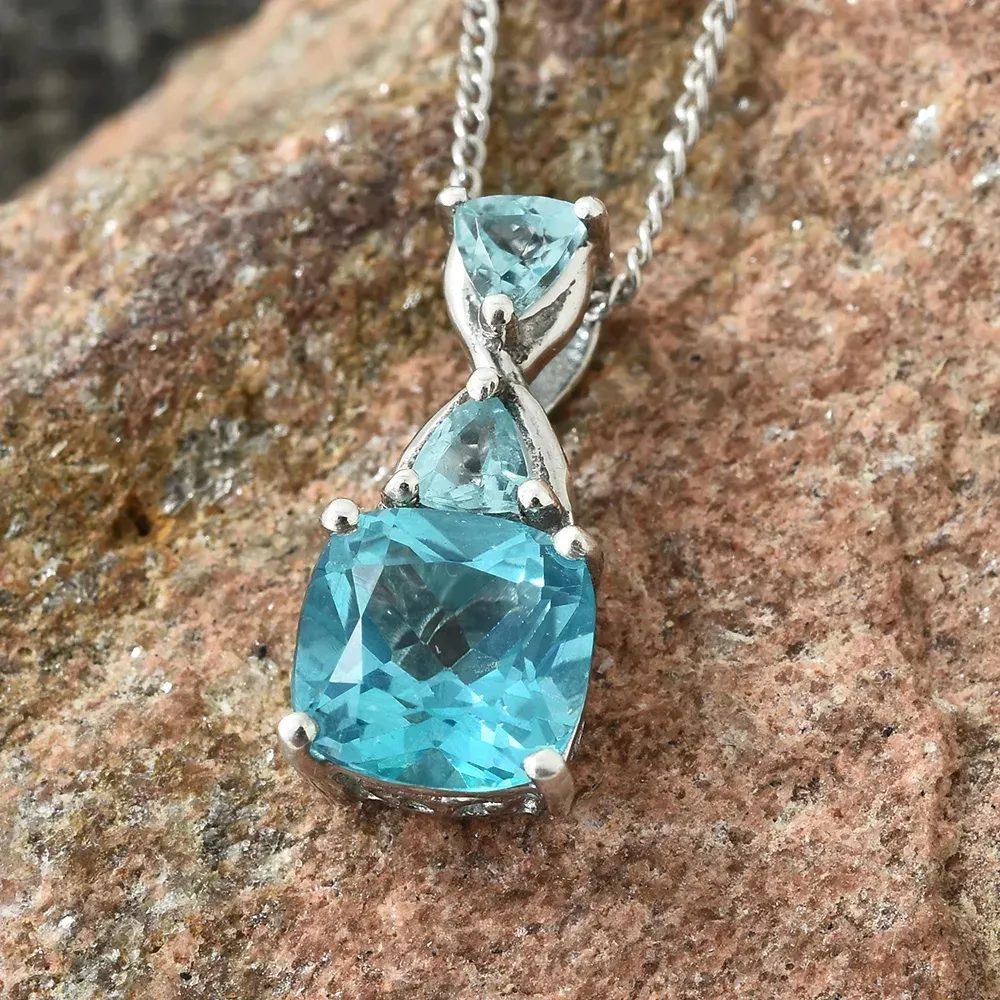 Closeup of blue topaz necklace against rock.