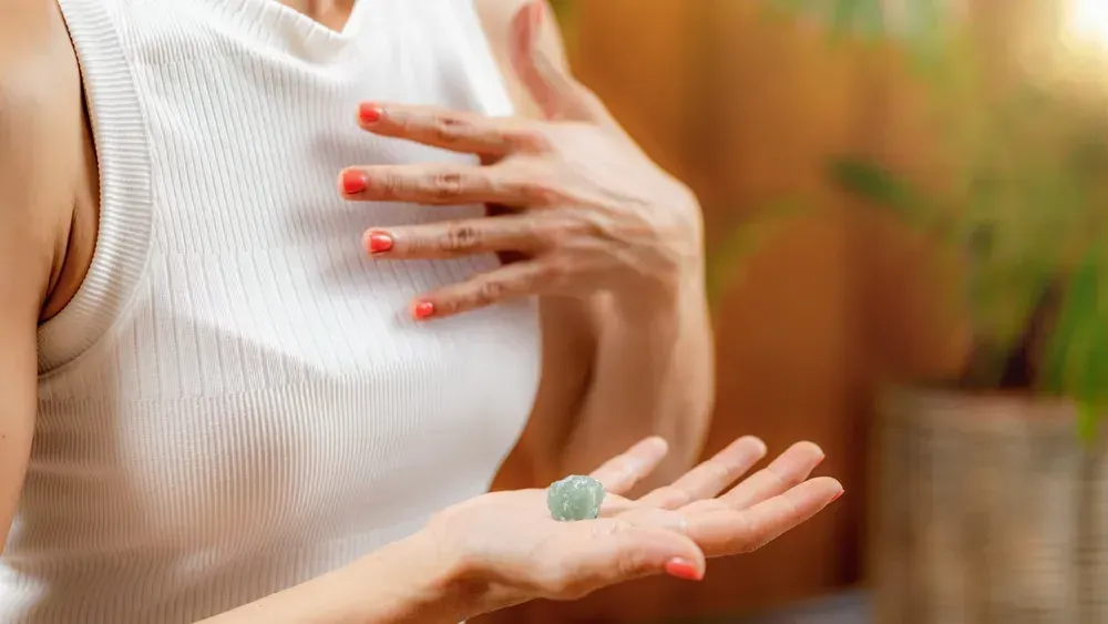 Woman holding green crystal in her palm. 
