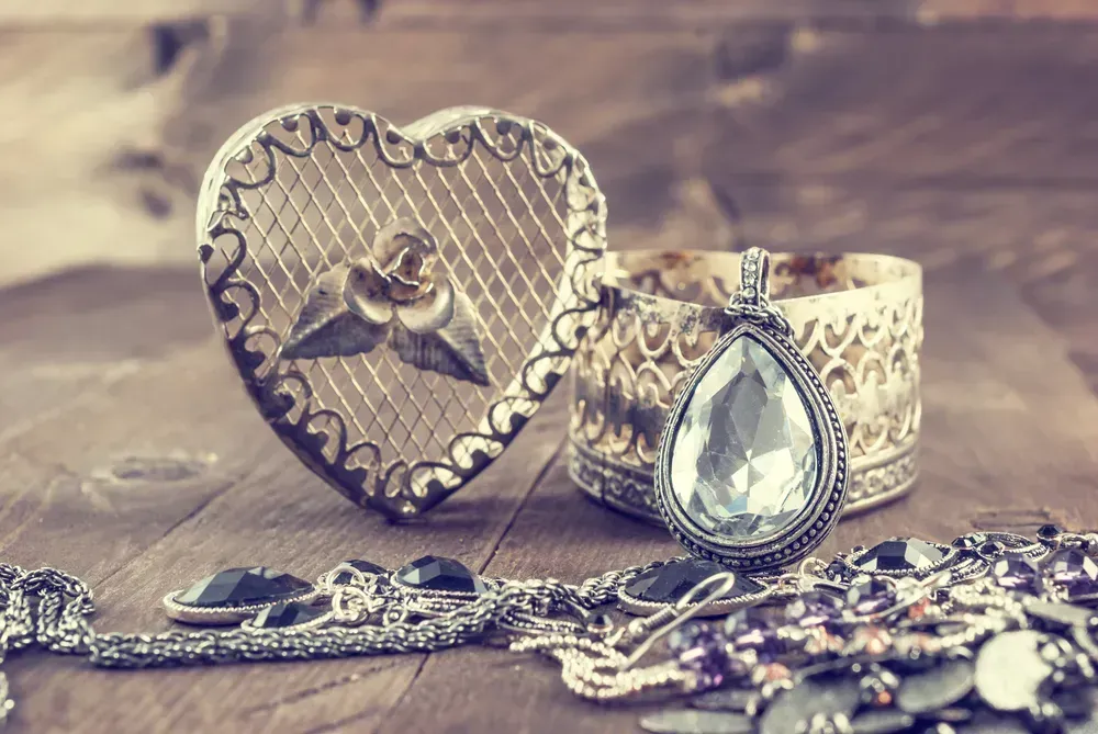 Vintage oval pendant with shiny stone and jewelry on wooden background.