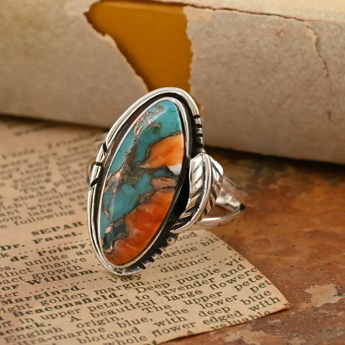 Santa Fe Style Spiny Turquoise Ring against natural paper and stone textured background. 