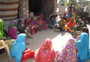 Tribal Indians gathered together outdoors, wearing traditional clothing.